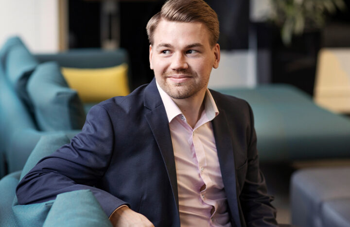 Vastuullisuusanalyytikko Mikko Noronen istumassa sohvalla hymyillen