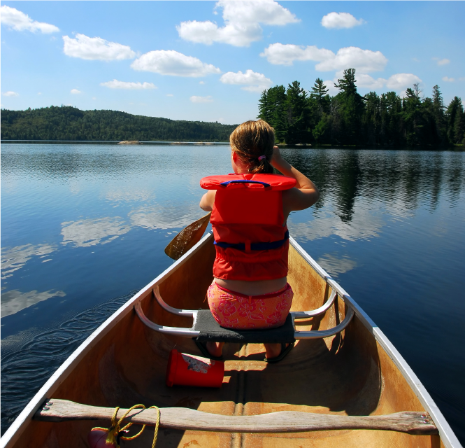 Lapsi soutaa veneellä suomalaisessa, kesäisessä, järvimaisemassa.